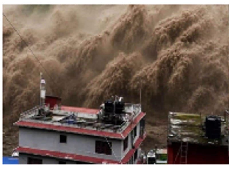 A surge of floodwater rising past the rooftop of a riverside building