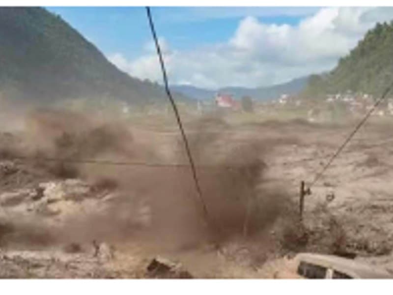 Floodwater sweeping through a valley settlement